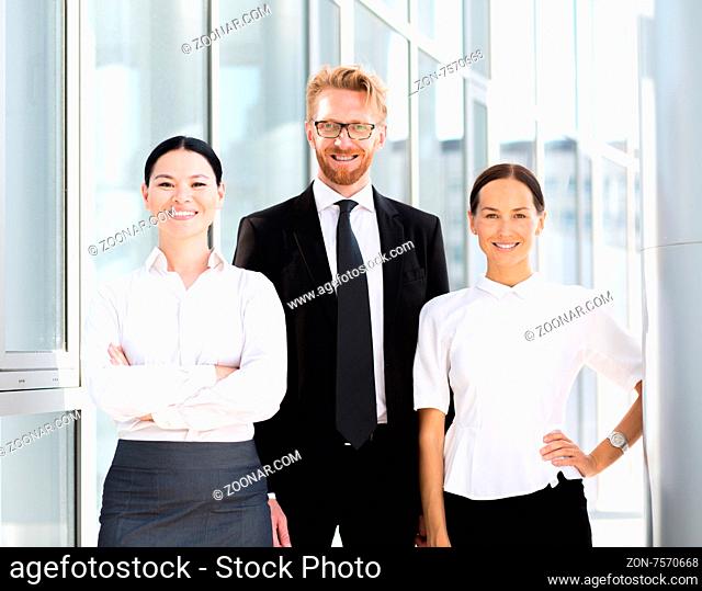 Group of businesspeople standing together. Man in business suit with his collegues women in white shirt smiling