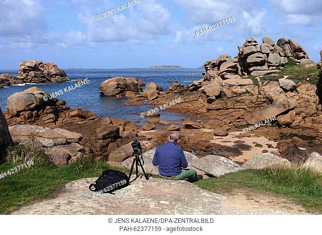 A photographer is waiting for the right light at the coastal stretch Cote de Granit Rose in Ploumanach, France, 25 September 2015