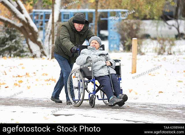 RUSSIA, MOSCOW - OCTOBER 27, 2023: A man and a woman on a wheelchair walk after a snowfall. Sergei Fadeichev/TASS