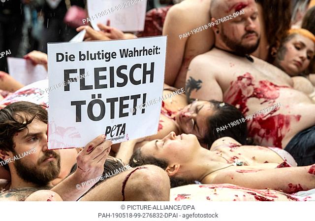 18 May 2019, Baden-Wuerttemberg, Stuttgart: Activists of the animal rights organization Peta lie on the floor, smeared with artificial blood and half-naked