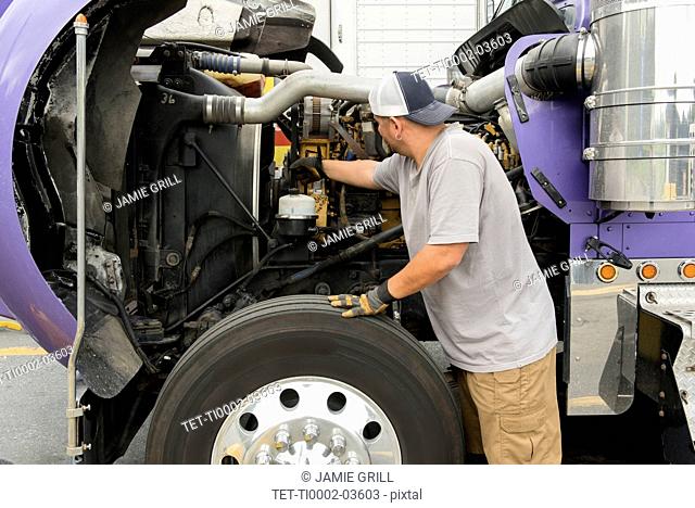 Truck driver checking semi-truck engine