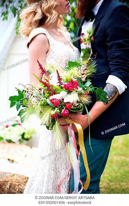 guy in a white shirt and a girl in a white wedding dress with bouquet of flowers