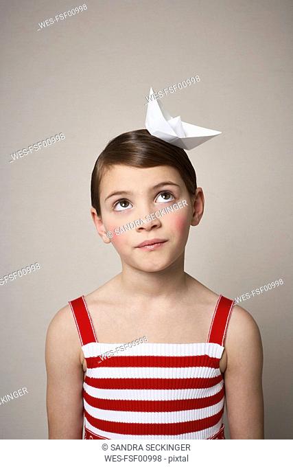 Portrait of little girl with paper boat on her head