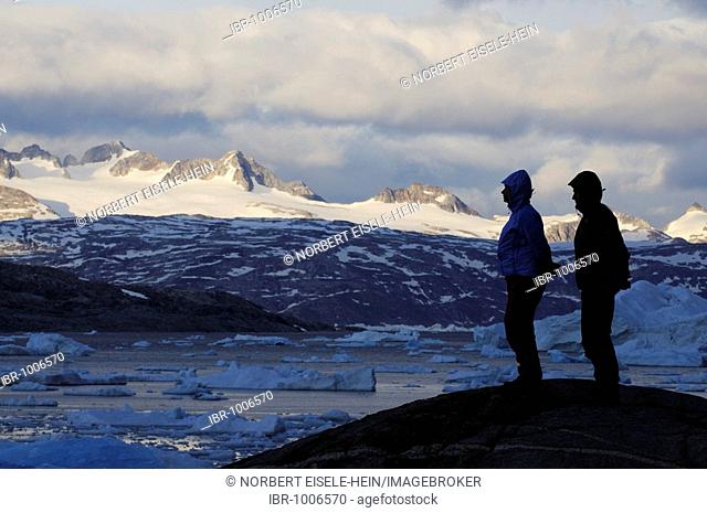 Hikers in front of icebergs in the Johan Petersen Fjord, East Greenland, Greenland