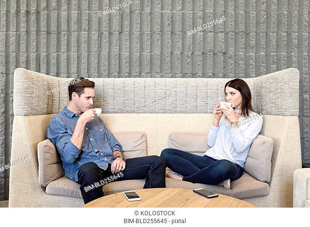 Caucasian couple relaxing on sofa drinking coffee