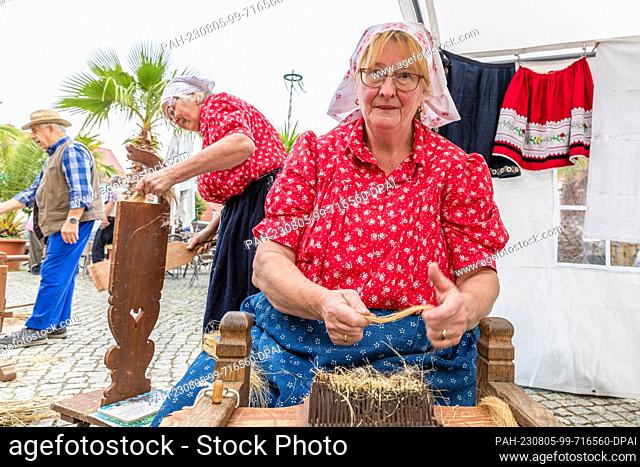 05 August 2023, Brandenburg, Golßen: Members of the traditional costume group ""Nowa Niwa"" demonstrate the processing of flax at the Spreewald Cucumber Day in...