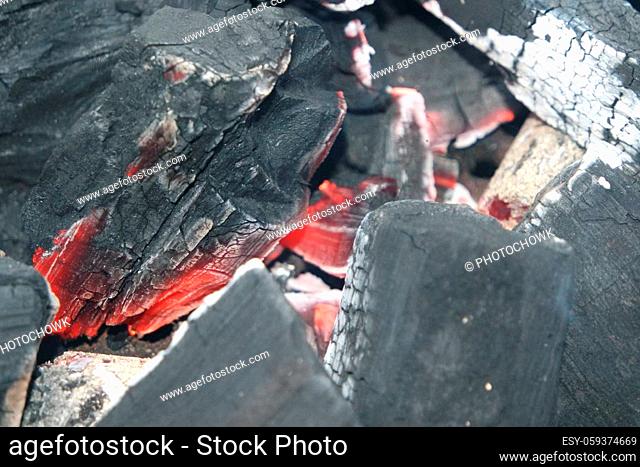 Fire on logs in fire pot with embers and burning coal. Bonfire with blazing red and orange fire flames. Fire background with woods and planks on fire at night...