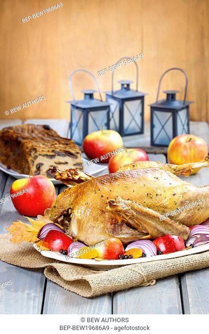 Roasted goose with apples and vegetables on wooden table. Festive dish