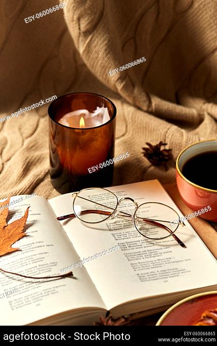 book, glasses, coffee and candle in autumn