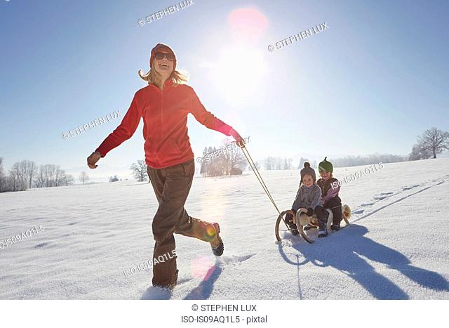 Mother pulling sons along on sled