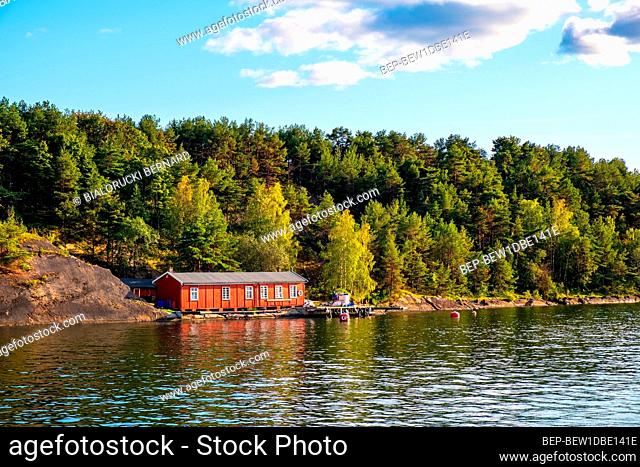 Oslo, Ostlandet / Norway - 2019/09/02: Panoramic view of Gressholmen island on Oslofjord harbor with summer cabin house at wooded shoreline in early autumn
