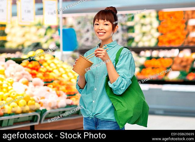 asian woman with food in bag eating wok at store