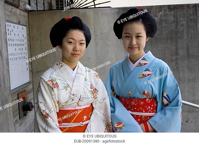 Two Maiko apprentice Geisha wearing patterned kimono, standing outside their house in the Gion District, the neighbourhood where Geisha live, study and perform