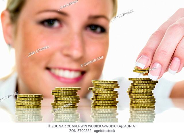 Eine junge Frau stapelt Münzen. Symbolfoto für sparen, Wachstum, Vorsorge