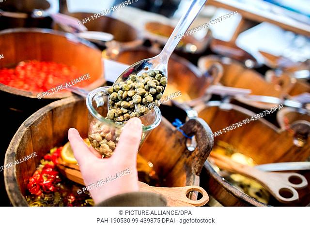 08 March 2019, Lower Saxony, Oldenburg: A woman fills fresh capers into a reusable glass at a weekly market. With the growing environmental awareness among...