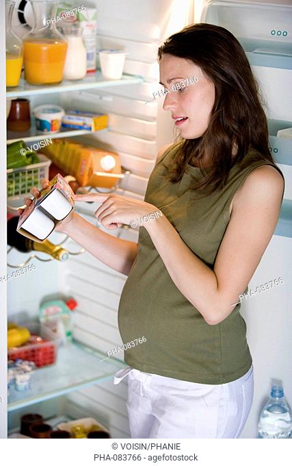 Pregnant woman checking the expiration date of food
