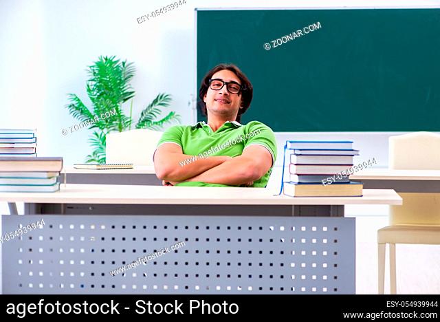 Young male student in front of green board