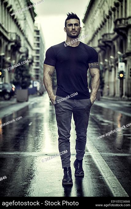 Handsome muscular man with tattoo posing in European city center, Turin, Italy