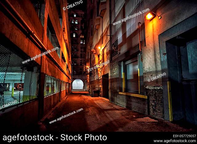 Dark and eerie downtown urban city alley with a loading dock next to a parking garage at night