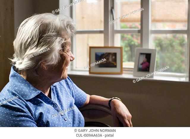 Senior adult woman sitting in room looking out of window