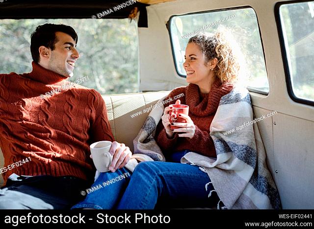 Happy couple having coffee in van on weekend