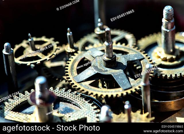 Close up metal gears mechanism. Golden colours. Hard light. Clock interior mechanism parts