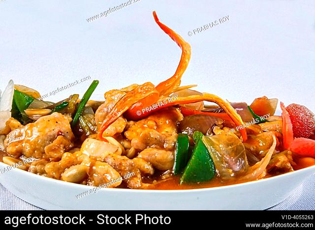 Boneless chilli chicken with red peppers is a exotic and mouthwatering Thai food served in a ceramic bowl on a white background