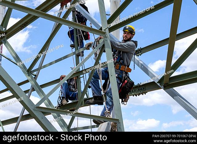 06 July 2020, Saxony, Heidenau: Technician Roman Beu (right) climbs up the power pylon to his workplace. In Heidenau near Dresden in Saxony