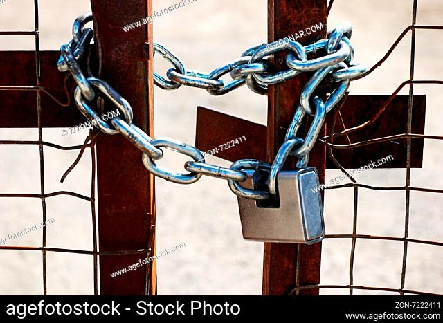 Padlock and chain on a metal gate in a privacy or safety and security concept