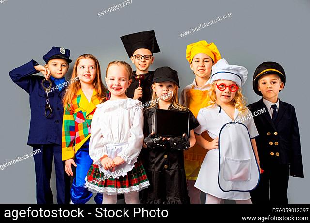 Group of school children dressing up as professions. Future education. Happy friends dressed as doctor, cook, judge, policeman, agent and singer