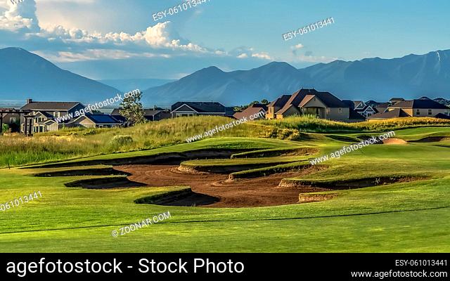 Panorama frame Scenic view of a golf course and residential area under blue sky on a sunny day. Sand bunkers can be seen amid the vibrant green fairway
