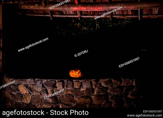 Abandoned well in the forest with Halloween pumpkin at night. Horror concept