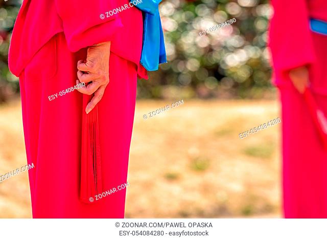 A woman holding red fan during Tai Chi exercises at cultural and folklore festival