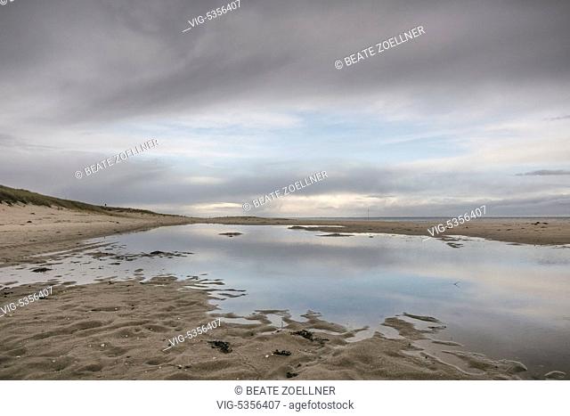 DEUTSCHLAND, HOERNUM/SYLT, 08.12.2014, Grosses Loch in der grauen Wolkendecke spiegelt sich auf dem Wasser am Wattenmeer noerdlich von Hoernum/Sylt -...