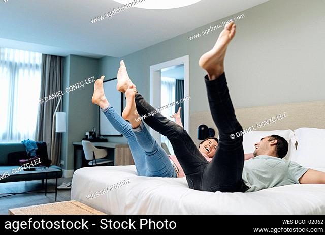 Carefree couple bouncing on bed in hotel room