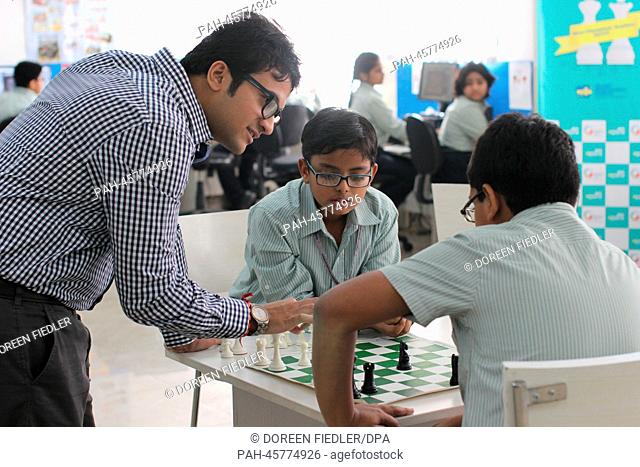 Chess teacher Nikhil Goshi (L) advises the pupils Arnav Pratap Singh (C, 9 years) and Suryaansh Jain (R, 10 years) while they play chess in the Global India...