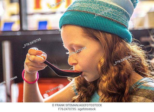 10 year old girl with woolen cap on, eating noodles in a noodle restaurant in Berkeley, CA, MR# 6063