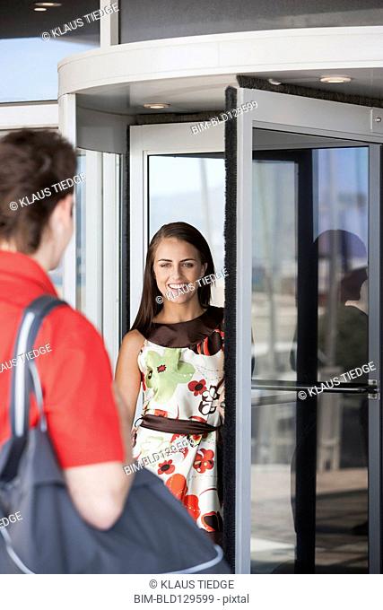 Caucasian couple greeting at revolving door
