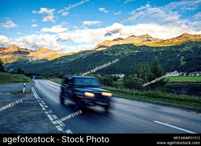 Off-Road car driving along asphalt road in Engadin valley
