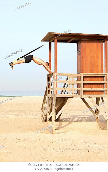man playing sports on the beach with trx