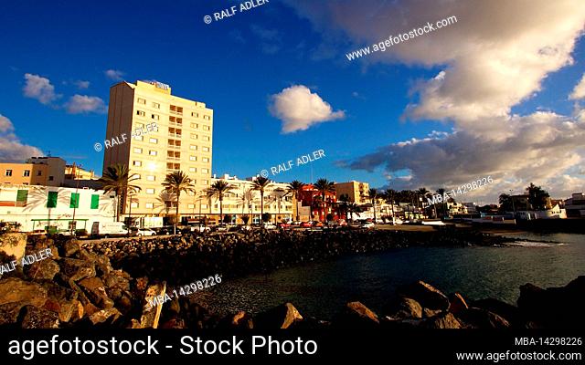 Spain, Canary Islands, Fuerteventura, capital, Puerto del Rosario, view over the water of the harbor to harbor promenade and row of buildings behind