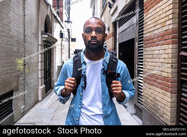 Man with backpack standing in alley