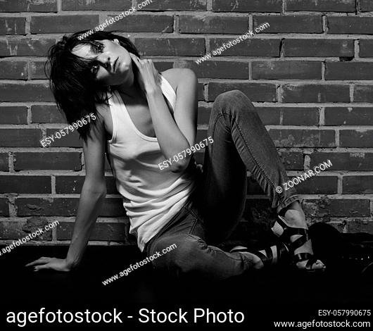 Androgyny female model in Heroin chic style near brick wall. Old style tinted image