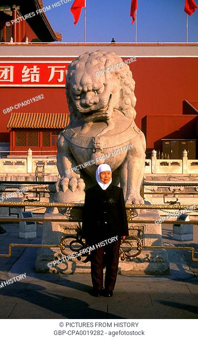 China: A visitor from China's large Muslim community poses in front of an imperial guardian lion at the Gate of Heavenly Peace (Tiananmen), Beijing