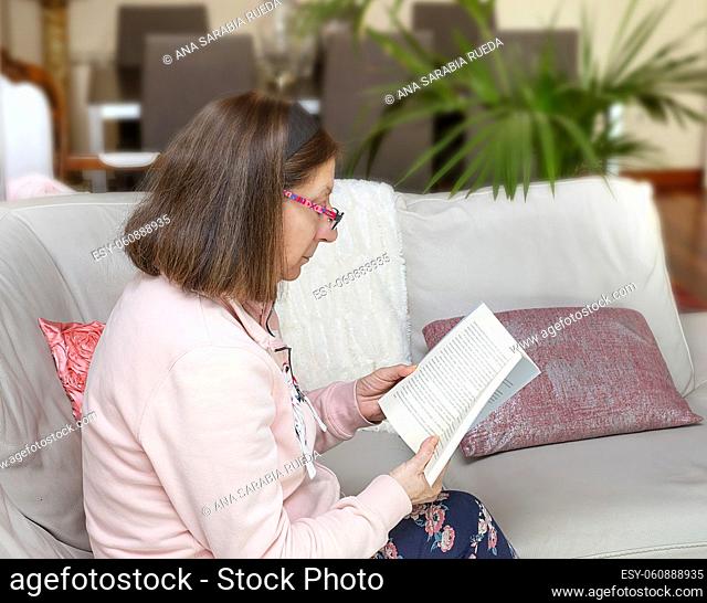 Relaxed older woman reads on the sofa at home
