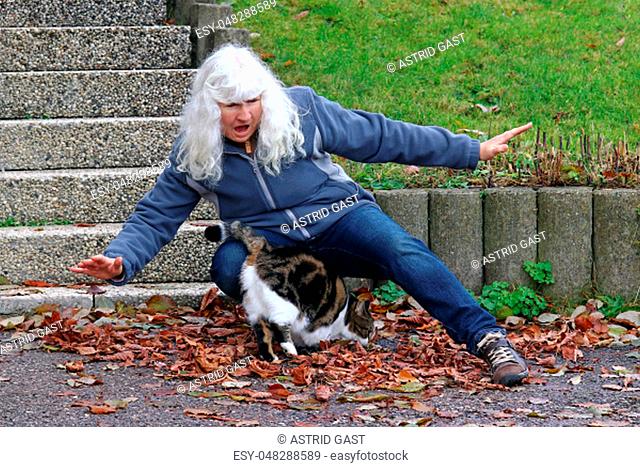 Risk of accident from pets. An elderly woman stumbles over a cat