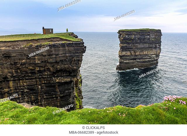 Downpatrick Head, Ballycastle, County Mayo, Donegal, Connacht region, Ireland, Europe. A man watching the sea stack from the top of the cliff