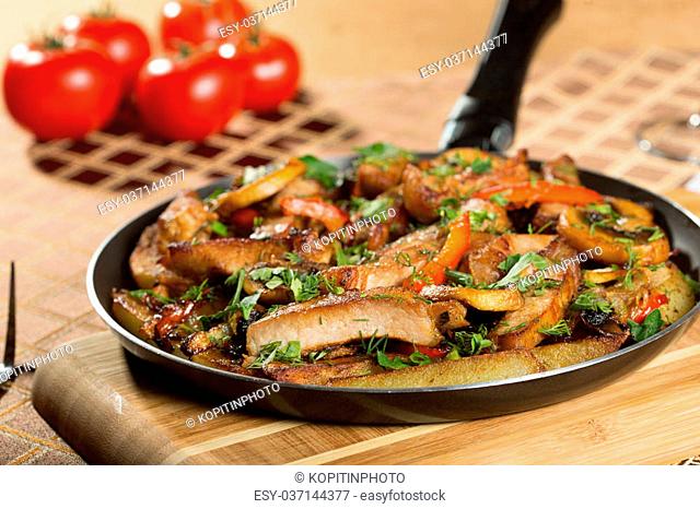 roast meat in a frying pan. fried vegetables and beef