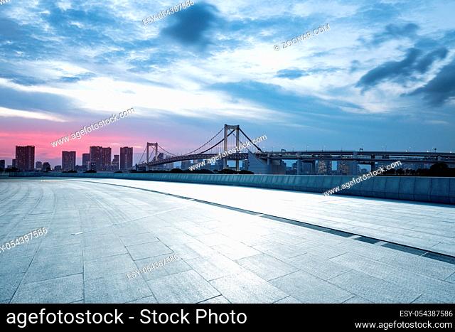 empty pedestrians sidewalk with modern suspension bridge in tokyo against cloud sky at twilight