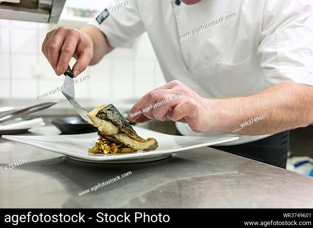Chef finishing fish on plate in restaurant
